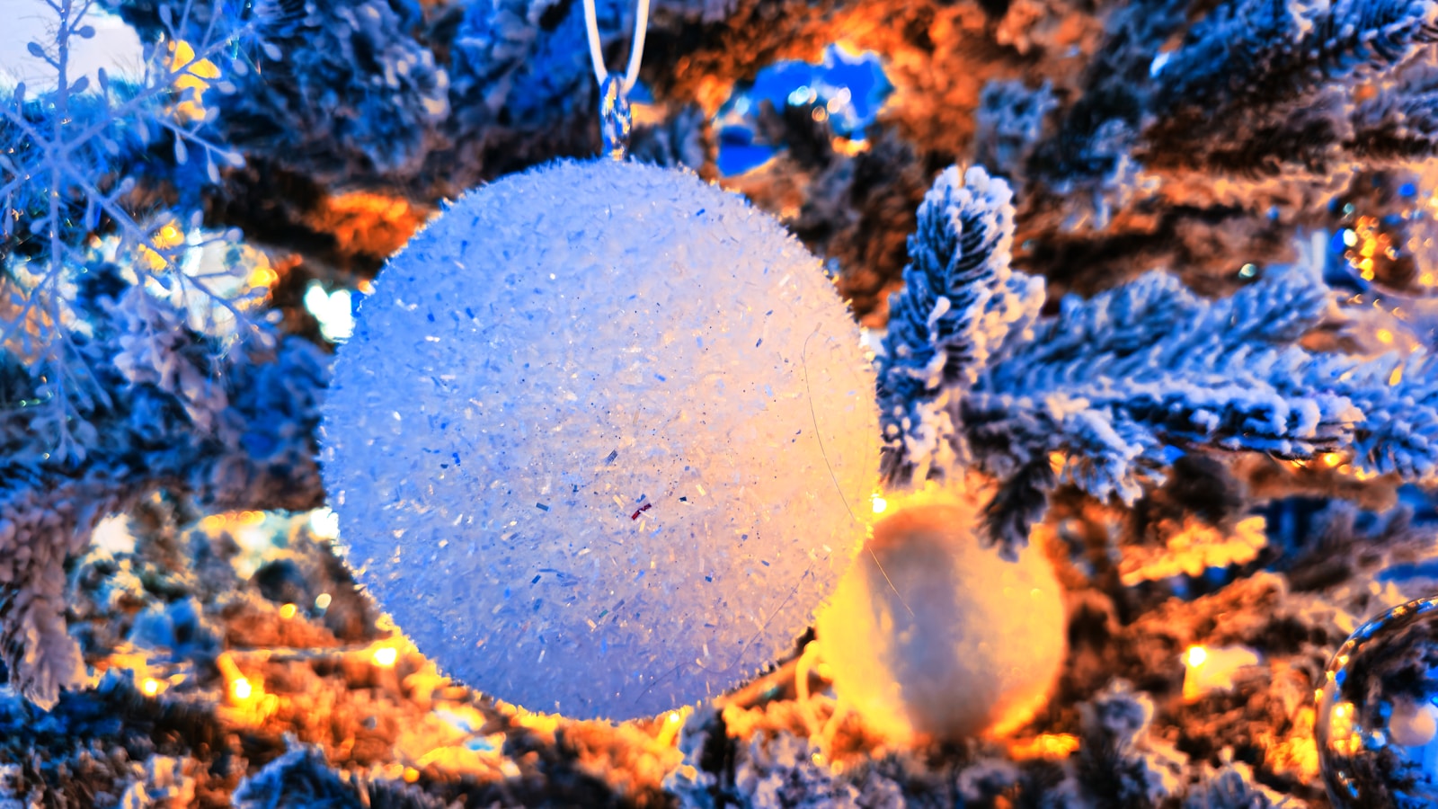 A blue ornament hanging from a christmas tree